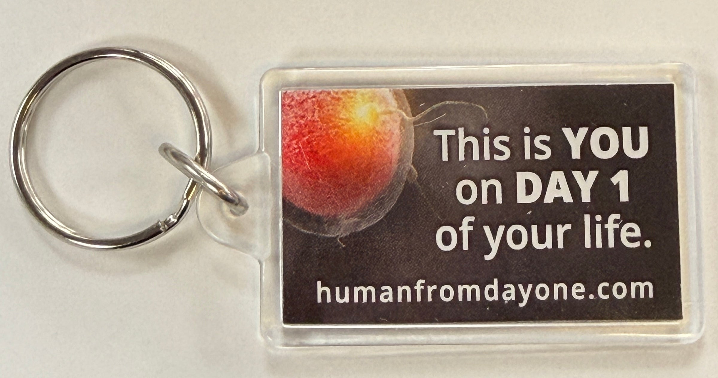 Keychain with motivational message on a card, displayed on a textured surface.
